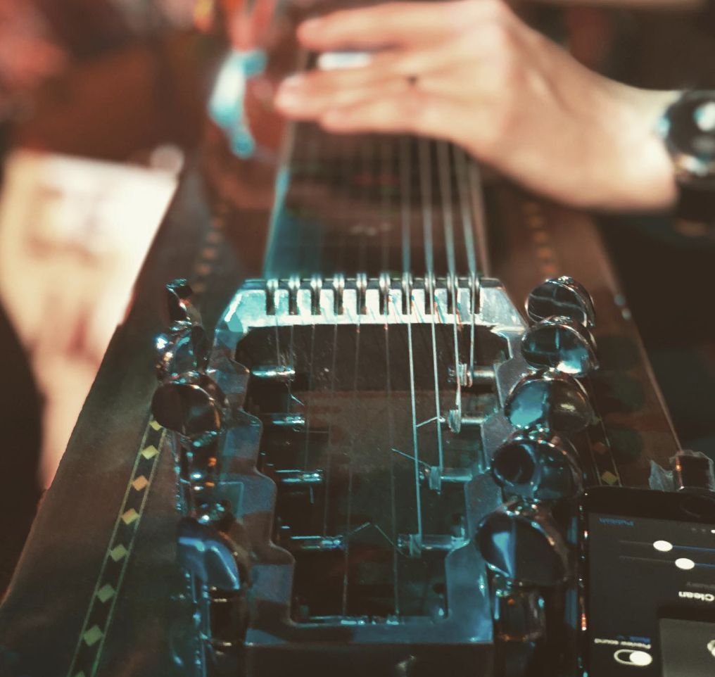 Close-up of pedal steel guitar under teal stage lighting